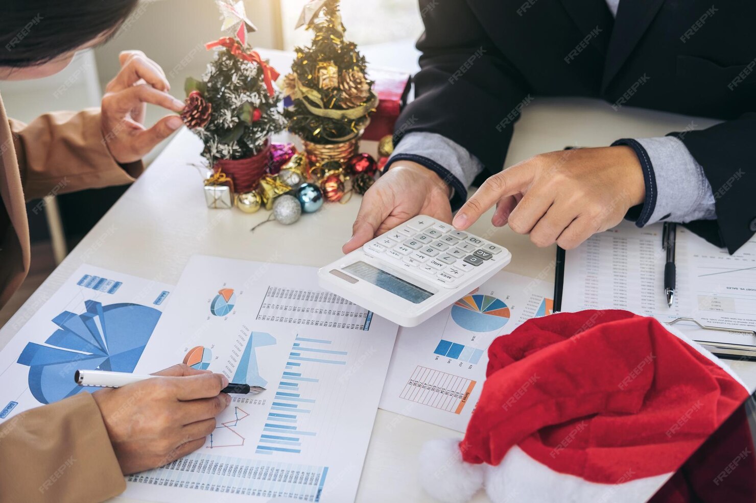 midsection-business-colleagues-discussing-graph-with-christmas-decorations-table_28283-6414